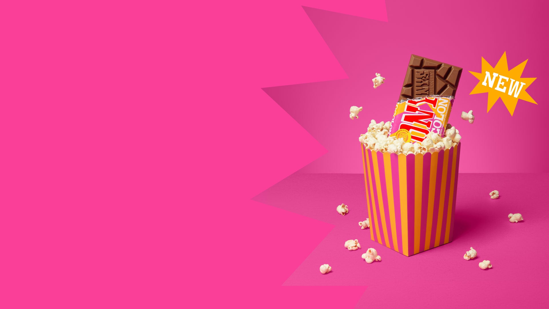 Popcorn bucket with Tony's Chocolonely milk popcorn crunch bar on a pink background
