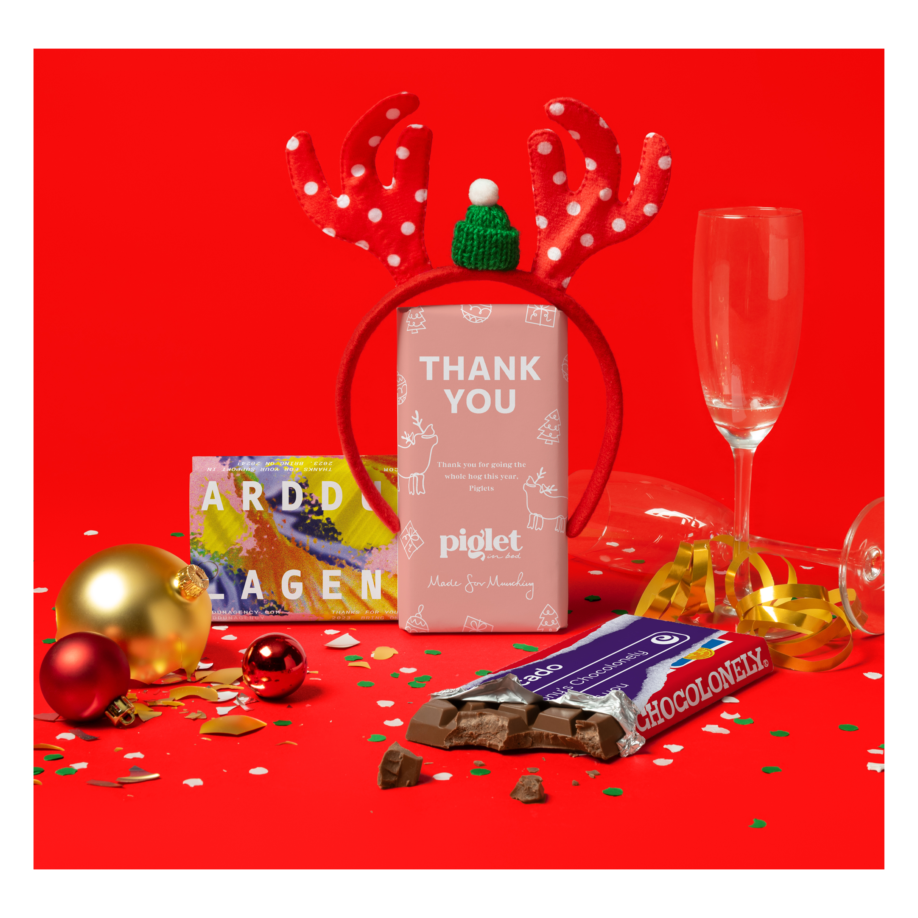 Tony's Chocolonely chocolate bars with personalized Christmas wrappers, some festive elements such as ornaments, glass and ribbon.